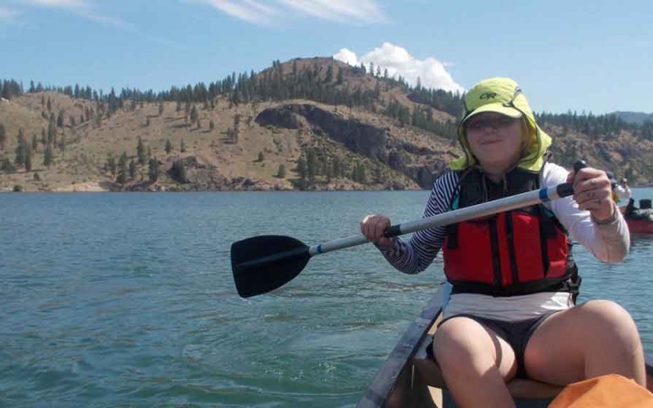 a student paddles a canoe on an outward bound expedition in the pacific northwest